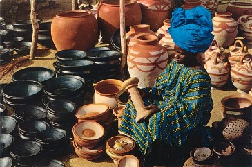 Featured is a 1960s postcard image of a Nigerian woman selling local pottery at the market in Illorin, Nigeria.  Photo by Irish photographer John Hinde.  The original unused postcard is for sale in The unltd.com Store.
